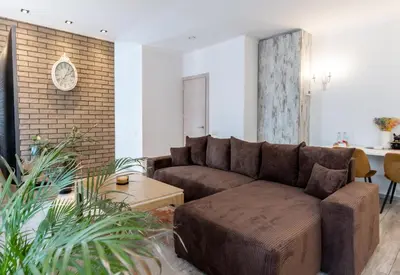 a living room with a brown couch and a brick wall at Vincent Heritage Appartments - Near Clinic, Arena and Stadium in Kaunas