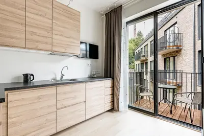 a kitchen with wooden cabinets and a balcony at City center studio, 24 in Vilnius