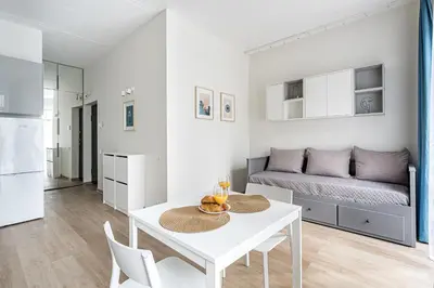 a white living room with a table and a bed at City center studio, parking, 16 in Vilnius