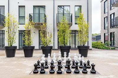 a chessboard in front of a building with potted plants at City center studio, parking, 16 in Vilnius