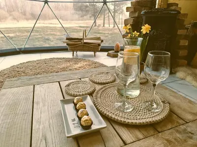 a wooden table with wine glasses and cookies on it at Miško Pašvaistėje - poilsis gamtoje in Balneliškiai