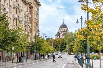 a man walking down a city street with a building at City Center apartment, 8 in Vilnius