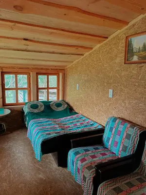 a room with two beds and a chair in a cabin at Sodyba Pas Juzi in Alanta