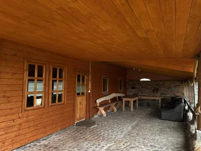 a porch of a wooden cabin with a wooden ceiling at Sodyba Pas Juzi in Alanta