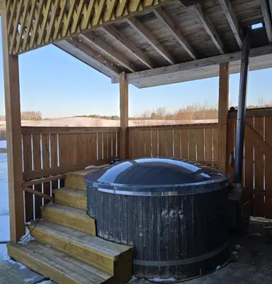 a hot tub under a pergola on a deck at Sodyba Pas Juzi in Alanta