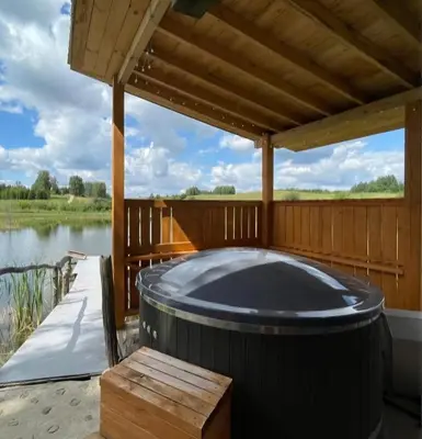 a hot tub on a deck next to a lake at Sodyba Pas Juzi in Alanta
