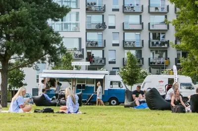 people sitting in the grass in front of a building at OZO Park city center in Vilnius