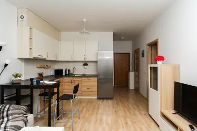 a kitchen and living room with a table and a refrigerator at OZO Park city center in Vilnius