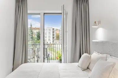 a white bedroom with a bed and a balcony at City center, 91 with parking in Vilnius
