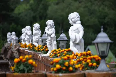 a row of statues of children on a wall with flowers at Sodyba Jums in Bijūnai