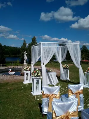 an outdoor ceremony with white chairs and a canopy at Sodyba Jums in Bijūnai