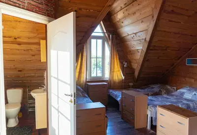 a bedroom with two beds and a bathroom in a log cabin at Sodyba Jums in Bijūnai