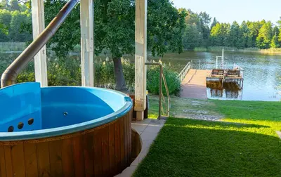 a large blue bath tub sitting next to a lake at Sodyba Jums in Bijūnai