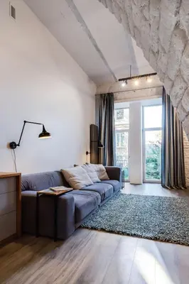 a living room with a couch and a stone wall at Old Brewery Loft in Paupys by Urban Rent in Vilnius