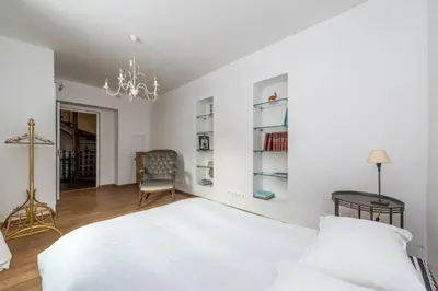 a white bedroom with a bed and a chair at City center, free parking, 4A in Vilnius
