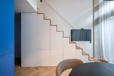 a staircase in a living room with a table and chairs at Paupys Central Lofts by Reside Baltic in Vilnius