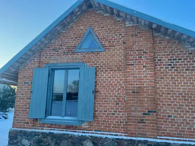 a brick building with a blue window on it at Ledainė in Naujasodis