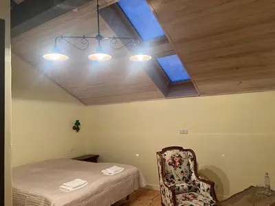 a room with a bed and a chair and windows at Ledainė in Naujasodis