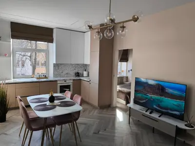 a kitchen and a living room with a table and a tv at Jaukus butas Šiaulių centre in Šiauliai