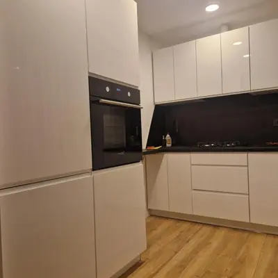 a kitchen with white cabinets and black appliances at Nauji centro apartamentai in Panevėžys