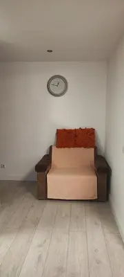 a bed in a room with a clock on the wall at Honey Apartament in Druskininkai