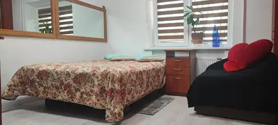 a bedroom with a bed and a dresser and windows at Amber Apartament in Druskininkai