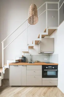 a kitchen with white cabinets and a staircase at Cozy & Stylish Loft near the city center in Vilnius