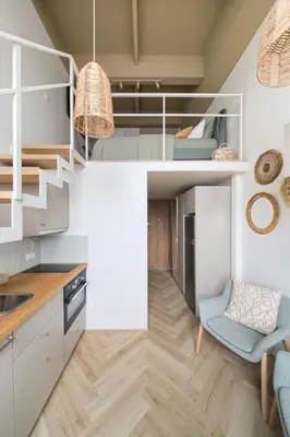 a small kitchen with white cabinets and a blue chair at Cozy & Stylish Loft near the city center in Vilnius