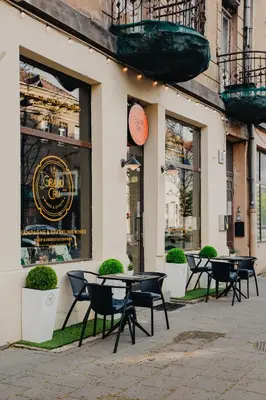 a group of tables and chairs in front of a building at Brand New Luxury Apartment, Parking, Center in Vilnius