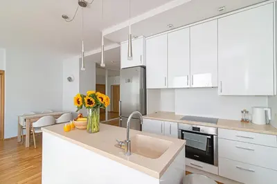 a kitchen with white cabinets and a vase of flowers on a counter at Bright 1 BDR apartment in Vivid Paupys by URBAN RENT in Vilnius