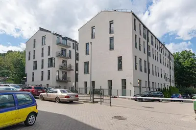 a large white building with cars parked in a parking lot at Bright 1 BDR apartment in Vivid Paupys by URBAN RENT in Vilnius