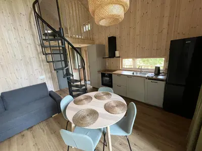 a kitchen with a table and chairs and a spiral staircase at Gilužio sodyba in Girsteitiškis