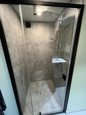 a shower with a glass door and a sink at Gilužio sodyba in Girsteitiškis