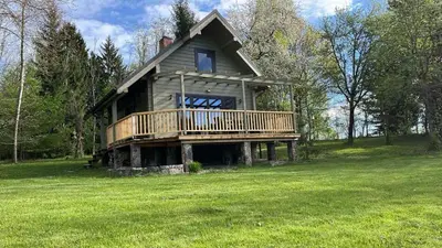 a large house with a deck on a green field at Gilužio sodyba in Girsteitiškis