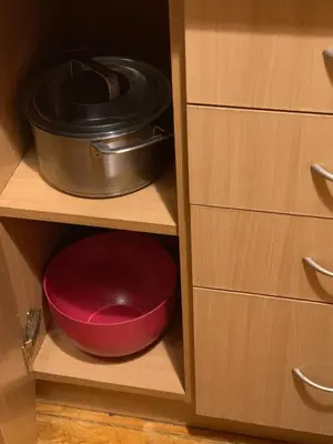 a red bowl and a pot in a cabinet at Minties apartment in Vilnius