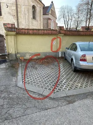 a red hose attached to a car parked next to a house at Old Town Apartment Free parking in Vilnius
