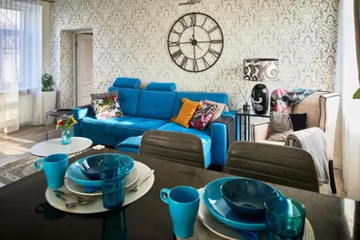 a living room with a blue couch and a clock at Old Town Apartment Free parking in Vilnius