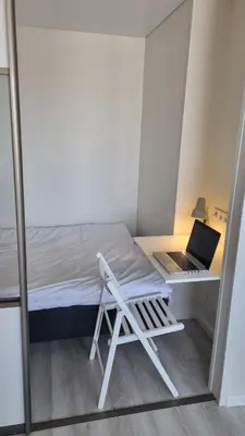 a small room with a bed and a laptop on a desk at Tiny cozy apartment 'Unihus' in Varėna