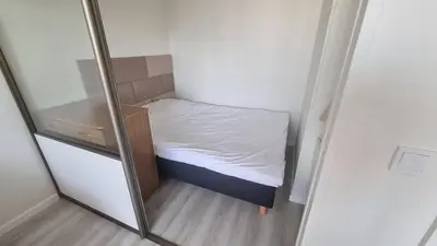 a small bed in a small room with a mirror at Tiny cozy apartment 'Unihus' in Varėna