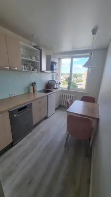 a kitchen with a table and a table and a window at Tiny cozy apartment 'Unihus' in Varėna