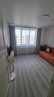 a living room with a couch and a large window at Tiny cozy apartment 'Unihus' in Varėna