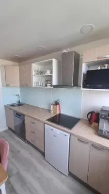 a kitchen with wooden cabinets and a counter top at Tiny cozy apartment 'Unihus' in Varėna