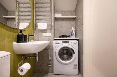 a small bathroom with a washing machine and a sink at Timeless Bliss Old Town Apartment by Reside Baltic in Vilnius