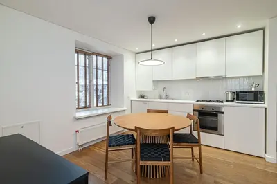 a kitchen with white cabinets and a wooden table and chairs at Stylish & Comfortable 1-Bedroom Apartment in Vilnius Old Town by URBAN RENT in Vilnius