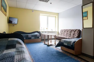 a room with two beds and a table and a chair at Eiva in Marijampolė