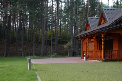 a log cabin with a porch and a grass field at Dzūkų sodžius in Snaigupė