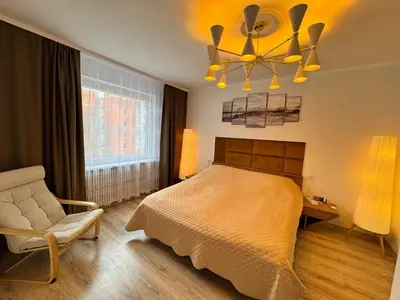 a bedroom with a bed and a chair and a chandelier at AUKŠTAS Ap in Visaginas