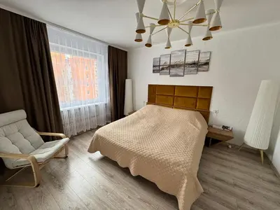 a bedroom with a bed and a chair and a chandelier at AUKŠTAS Ap in Visaginas