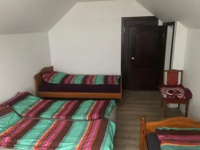 a bedroom with two beds and a door with a chair at Wind Mood in Klebiškis