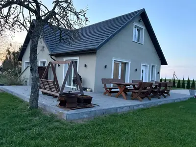 a picnic table and benches in front of a house at Wind Mood in Klebiškis